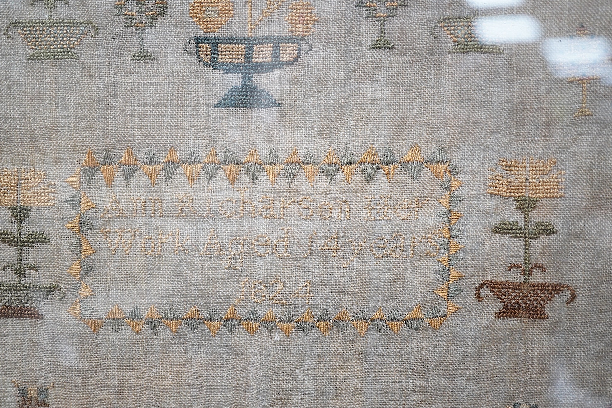 A sampler with spot motifs and central cartouche, embroidered with Ann Richardson, her work aged 14 years 1824. A very finely embroidered large spot sampler worked with motifs of stags, trees, planters of flowers with in